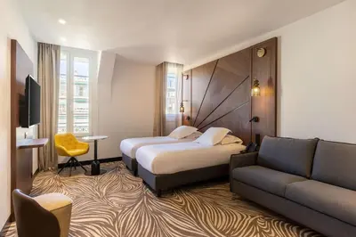 a hotel room with two beds and a couch at Hôtel Apollinaire Nice in Nice