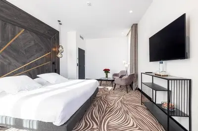 a hotel room with a bed and a flat screen tv at Hôtel Apollinaire Nice in Nice