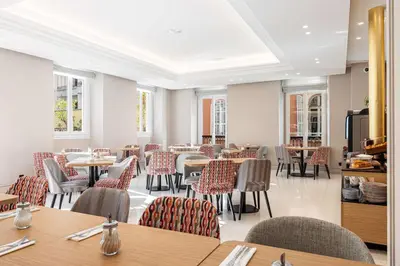 a dining room with tables and chairs and windows at Hôtel Apollinaire Nice in Nice