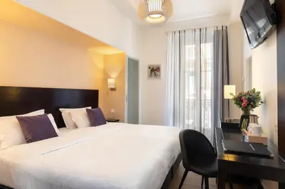 a hotel room with a large bed and a desk at Hotel Florence Nice in Nice