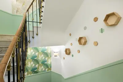 a staircase with a white wall with a green leaf wallpaper at Hotel Florence Nice in Nice