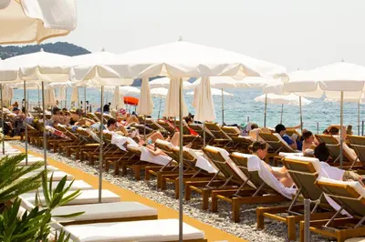 a group of people sitting in chairs on the beach at Hotel Villa Victoria in Nice