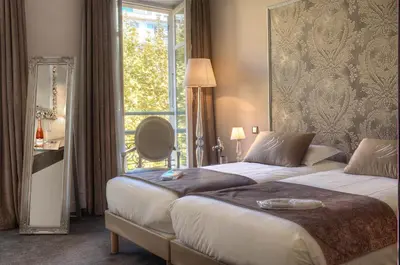 a hotel room with two beds and a window at Hotel Villa Victoria in Nice