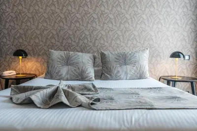 a bedroom with a bed with white sheets and two lamps at Hotel Villa Victoria in Nice