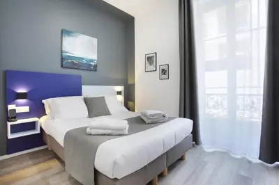 a bedroom with a large bed with a blue wall at Hôtel Alcôve Nice in Nice