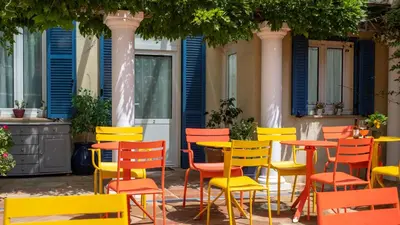 a group of colorful chairs and tables in a courtyard at Hôtel de la Fontaine in Nice