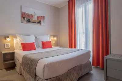 a bedroom with a bed with red curtains and a window at Hôtel de la Fontaine in Nice