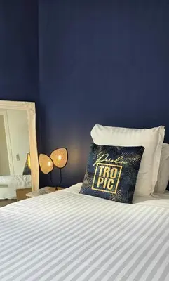a blue room with a bed with a pillow with a floor rug at Hôtel de la Fontaine in Nice