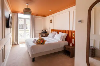 a bedroom with a bed and a large window at Hotel Ambassador, completely renovated in Nice