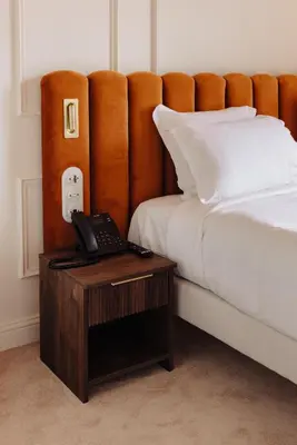 a bed with a phone on a wooden table next to a bed at Hotel Ambassador, completely renovated in Nice