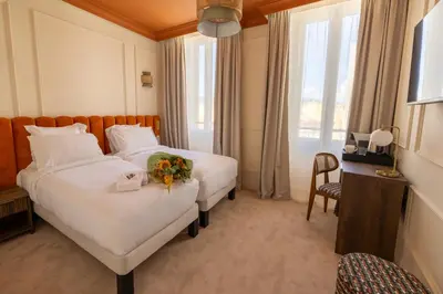 a hotel room with two beds with flowers on them at Hotel Ambassador, completely renovated in Nice