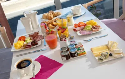 a white table with breakfast foods and a cup of coffee at Hotel Suisse in Nice