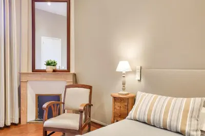 a bedroom with a bed and a chair and a fireplace at Hotel Lepante in Nice
