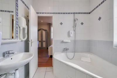 a bathroom with a bath tub and a sink at Hotel Lepante in Nice