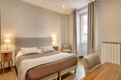 a bedroom with a bed and a chair and a window at Hotel Lepante in Nice