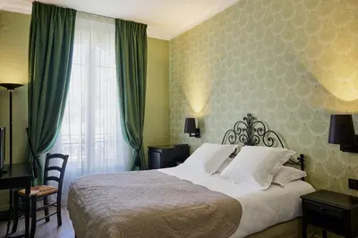 a bedroom with a bed with green curtains and a window at Hotel Le Grimaldi by Happyculture in Nice