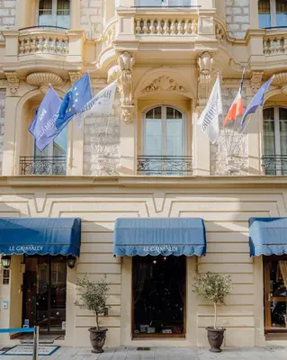 a building with blue and white flags on it at Hotel Le Grimaldi by Happyculture in Nice