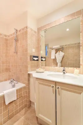 a bathroom with a sink and a tub and a mirror at Hotel Le Grimaldi by Happyculture in Nice