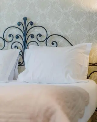 a bed with white pillows and a black headboard at Hotel Le Grimaldi by Happyculture in Nice