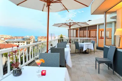 a restaurant with tables and umbrellas on a balcony at Splendid Hotel & Spa Nice in Nice