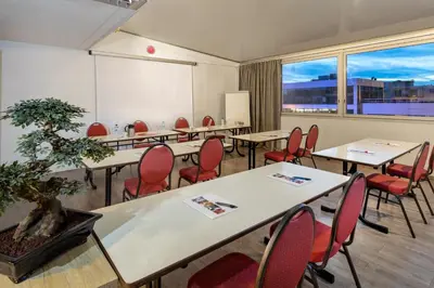 a room with tables and chairs and a large window at The Originals City, Hôtel Galaxie, Nice Aéroport in Saint-Laurent-du-Var