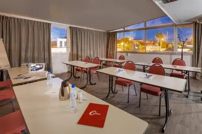 a conference room with tables and chairs and windows at The Originals City, Hôtel Galaxie, Nice Aéroport in Saint-Laurent-du-Var