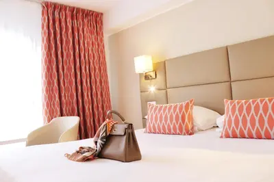 a hotel room with a bed and a desk and a window at Hotel Nice Riviera in Nice