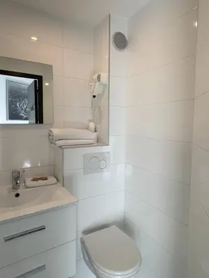 a white bathroom with a toilet and a sink at Trocadero in Nice