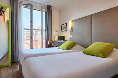 two beds in a hotel room with a window at Campanile Hotel Nice Centre Acropolis in Nice