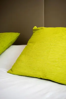 a bed with two lime green pillows on it at Campanile Hotel Nice Centre Acropolis in Nice