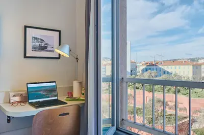 a laptop computer sitting on a desk next to a window at Campanile Hotel Nice Centre Acropolis in Nice