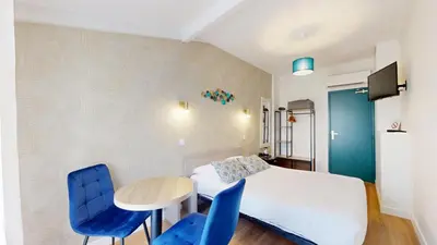 a bedroom with a bed and a table and blue chairs at Hotel Solara in Nice