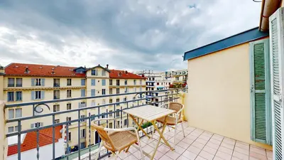 a table and chairs on a balcony with buildings at Hotel Solara in Nice