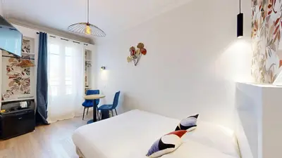 a white bedroom with a bed and a table at Hotel Solara in Nice
