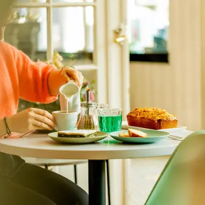 a woman is drinking coffee at a table with food at Hotel Aria in Nice