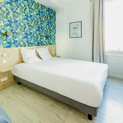 a bedroom with a large white bed in a room at Hotel Aria in Nice