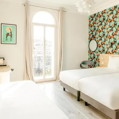 a bedroom with two beds and a window at Hotel Aria in Nice