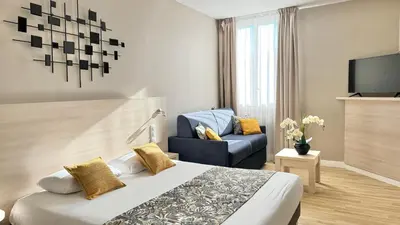 a hotel room with a bed and a blue chair at Hôtel Helvétique in Nice