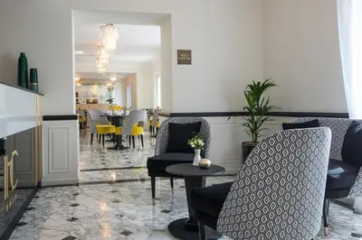 a lobby with chairs and a table and a dining room at Hotel Carlton in Beaulieu-sur-Mer