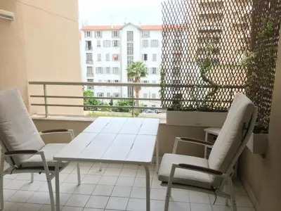 a white table and chairs on a balcony with a window at Quiet flat next to the beach in Nice