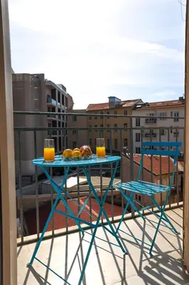 a table on a balcony with two glasses of orange juice at AzurAppart Brilliant 2room, Nice Massena in Nice