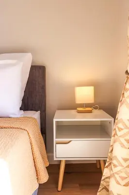 a bedside table with a lamp on it next to a bed at AzurAppart Brilliant 2room, Nice Massena in Nice