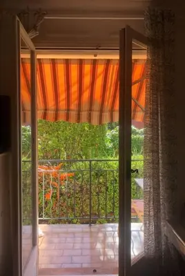 an open door to a balcony with an open curtain at Studio in the center of Saint-Jean-cap-Ferrat in Saint-Jean-Cap-Ferrat