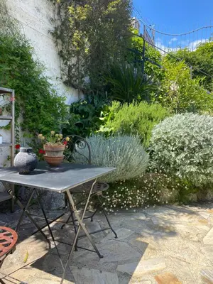 a table and chairs in a garden with plants at Petite chambre indépendante avec sdb, clim et parking privé in Nice