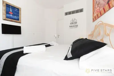 a white bed with black and white pillows on it at Mini Suite Bijou - Five Stars Holiday House in Nice