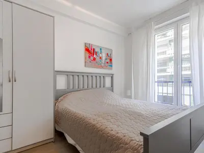 a white bedroom with a bed and a window at Apartment Le Mozart by Interhome in Nice