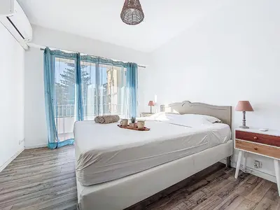 a white bedroom with a bed and a window at Apartment Le Clos tranquille by Interhome in Nice