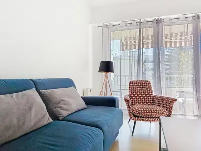 a living room with a blue couch and a chair at Apartment Le Clos tranquille by Interhome in Nice