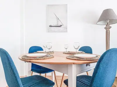 a dining room table with blue chairs and a lamp at Apartment Le Clos tranquille by Interhome in Nice