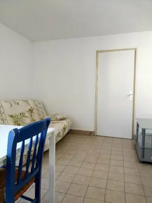a room with a bed and a table and a blue chair at Appartement F2 à 50 m de la plage in Nice